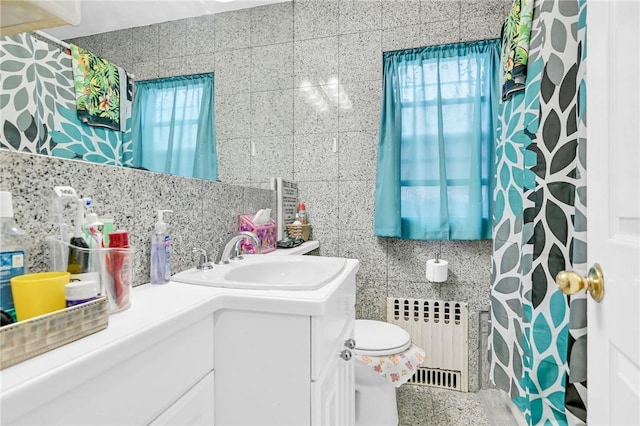 bathroom with radiator, tasteful backsplash, toilet, vanity, and tile walls