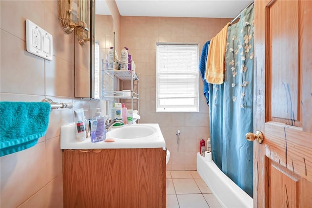 full bathroom featuring shower / bathtub combination with curtain, tile patterned floors, toilet, vanity, and tile walls