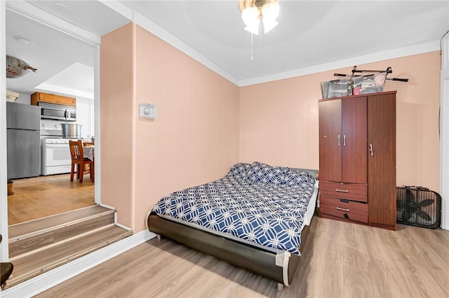 bedroom with stainless steel refrigerator, ceiling fan, crown molding, and light wood-type flooring