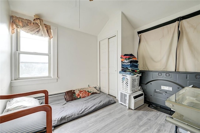 bedroom with a closet, light hardwood / wood-style flooring, and vaulted ceiling