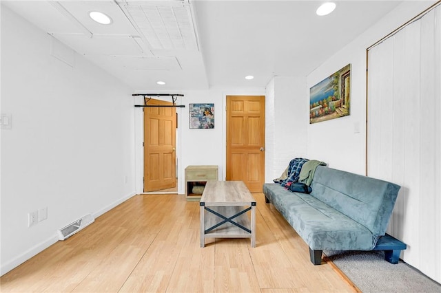 living area with wood-type flooring and a barn door