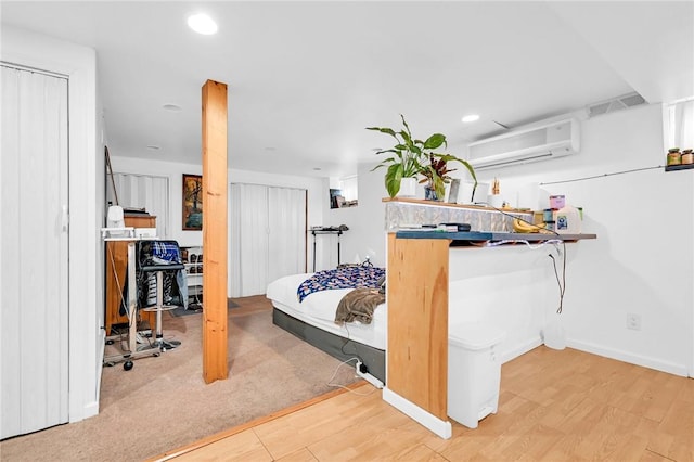 bedroom featuring a wall mounted air conditioner and light hardwood / wood-style floors