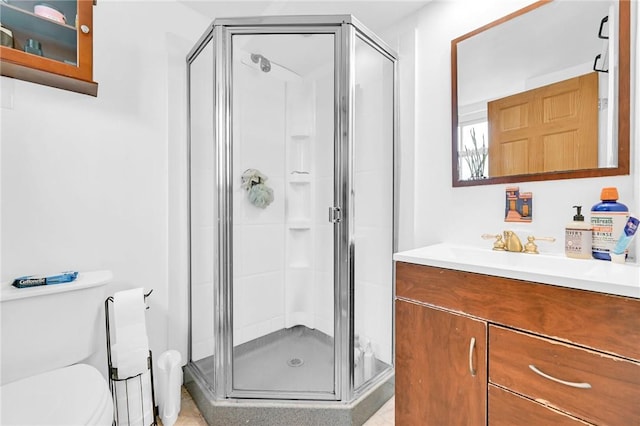 bathroom with vanity, toilet, and a shower with door