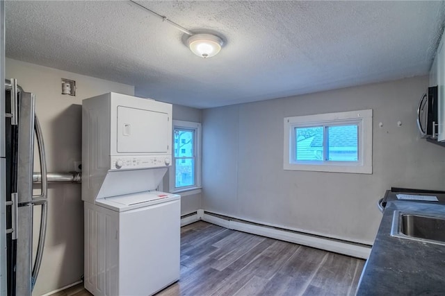 washroom with a textured ceiling, stacked washer and dryer, plenty of natural light, and dark wood-type flooring