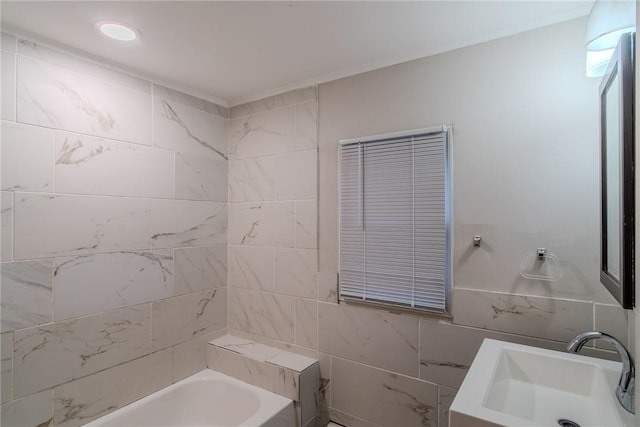 bathroom featuring a bath, sink, and tile walls