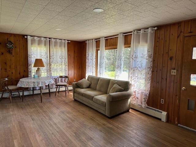 sitting room featuring wood walls, hardwood / wood-style floors, and a baseboard radiator