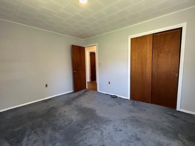 unfurnished bedroom featuring dark colored carpet and a closet