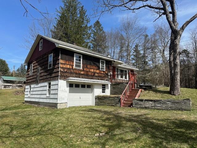 view of front facade featuring a garage, a deck, and a front yard