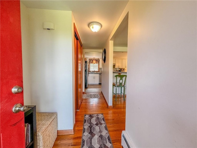 hallway with hardwood / wood-style floors and a baseboard heating unit