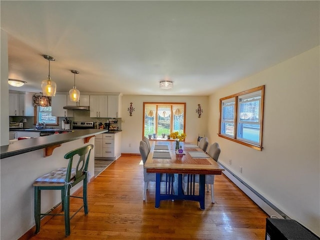 dining space with light wood-type flooring and baseboard heating