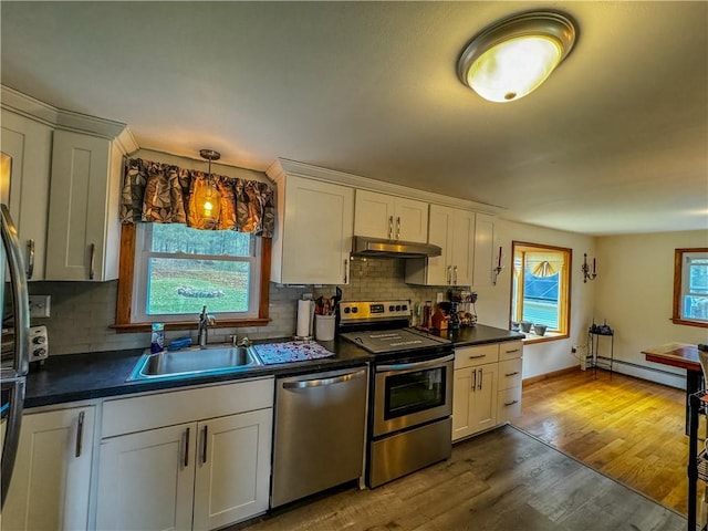 kitchen with sink, stainless steel appliances, baseboard heating, backsplash, and light hardwood / wood-style floors