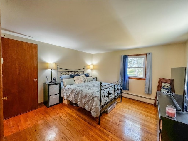 bedroom with hardwood / wood-style flooring and a baseboard heating unit