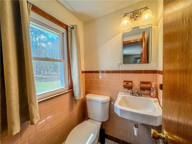 bathroom with toilet, sink, and tile walls