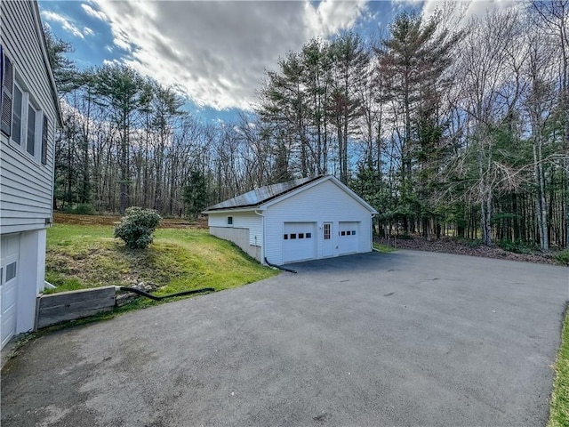 view of side of home featuring a lawn, a garage, and an outbuilding