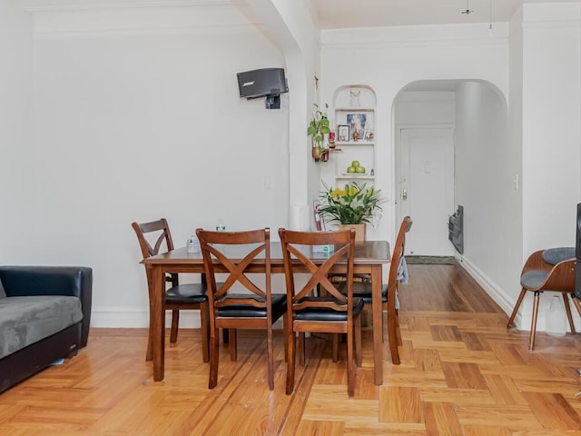 dining area featuring light parquet floors and crown molding