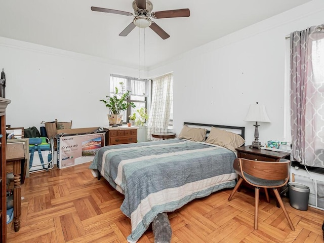 bedroom with ceiling fan, light parquet flooring, and ornamental molding