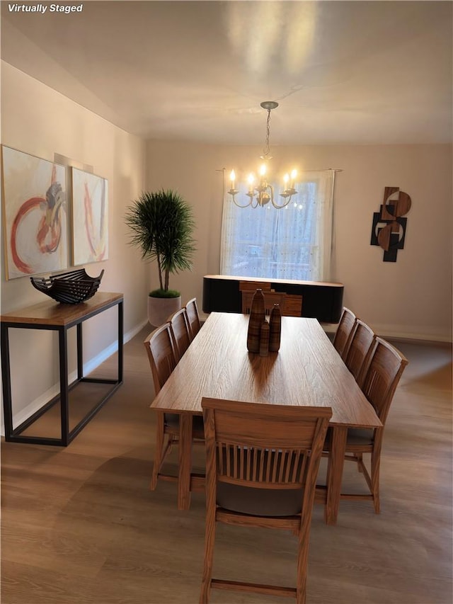 dining space with hardwood / wood-style flooring and a notable chandelier