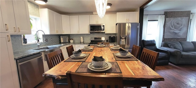 kitchen with dark wood-type flooring, sink, appliances with stainless steel finishes, tasteful backsplash, and white cabinetry