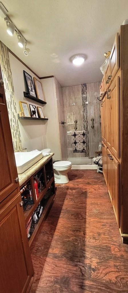 bathroom with tiled shower, wood-type flooring, vanity, and toilet