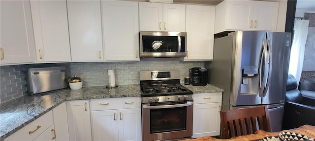 kitchen featuring dark stone countertops, white cabinets, appliances with stainless steel finishes, and decorative backsplash