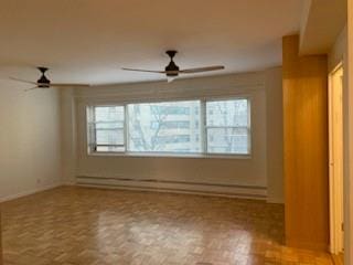 unfurnished room with ceiling fan, plenty of natural light, light parquet floors, and a baseboard heating unit