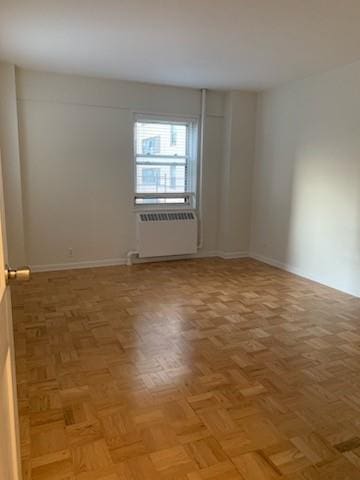 empty room with parquet floors and radiator