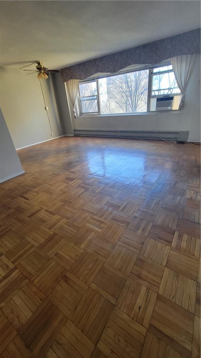 spare room with ceiling fan, dark parquet floors, cooling unit, and a baseboard radiator