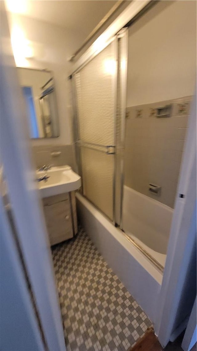 bathroom with sink and bath / shower combo with glass door