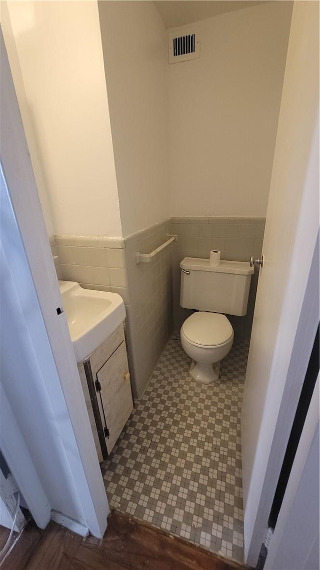 bathroom featuring sink, hardwood / wood-style floors, tile walls, and toilet