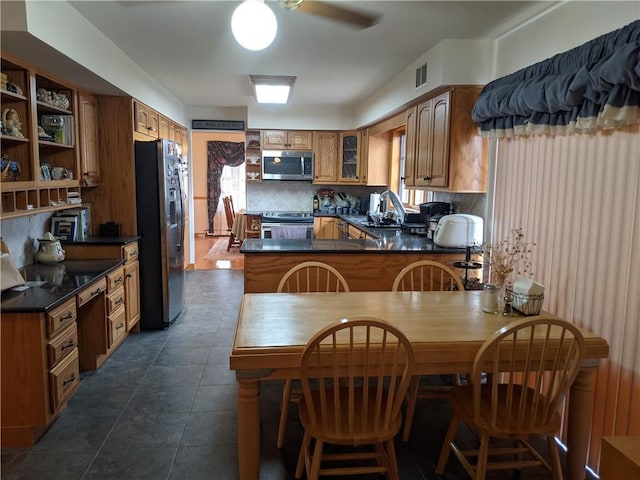 kitchen featuring kitchen peninsula, decorative backsplash, stainless steel appliances, sink, and dark tile patterned flooring