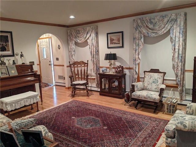 living area featuring hardwood / wood-style flooring, baseboard heating, and crown molding