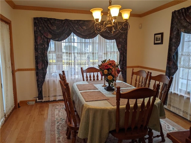 dining area with hardwood / wood-style flooring, a notable chandelier, ornamental molding, and a wealth of natural light