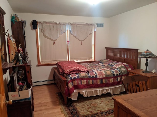 bedroom featuring light wood-type flooring and baseboard heating