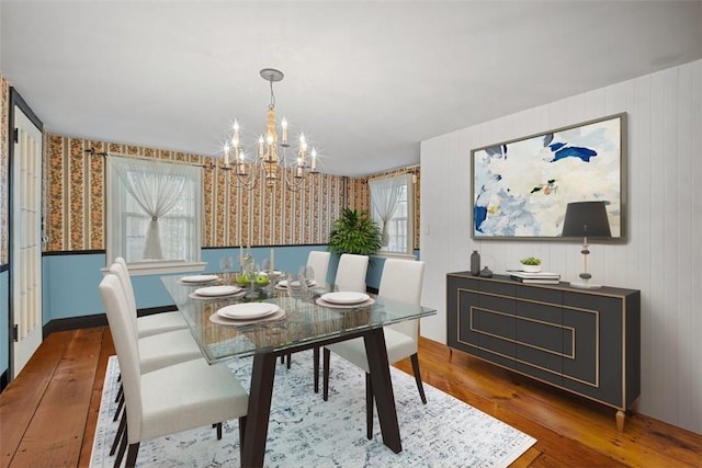 dining space with wood walls, dark wood-type flooring, and an inviting chandelier