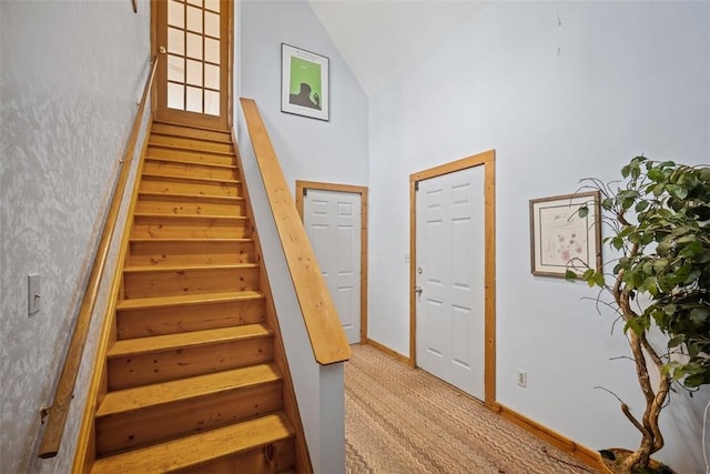 staircase with carpet and high vaulted ceiling