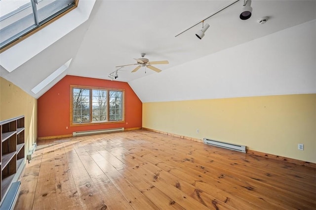 additional living space featuring light wood-type flooring, a baseboard radiator, vaulted ceiling, and ceiling fan