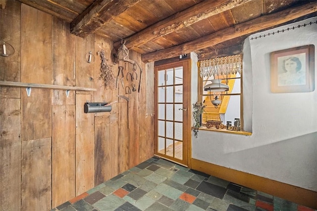 entryway with wooden walls, beamed ceiling, and wooden ceiling