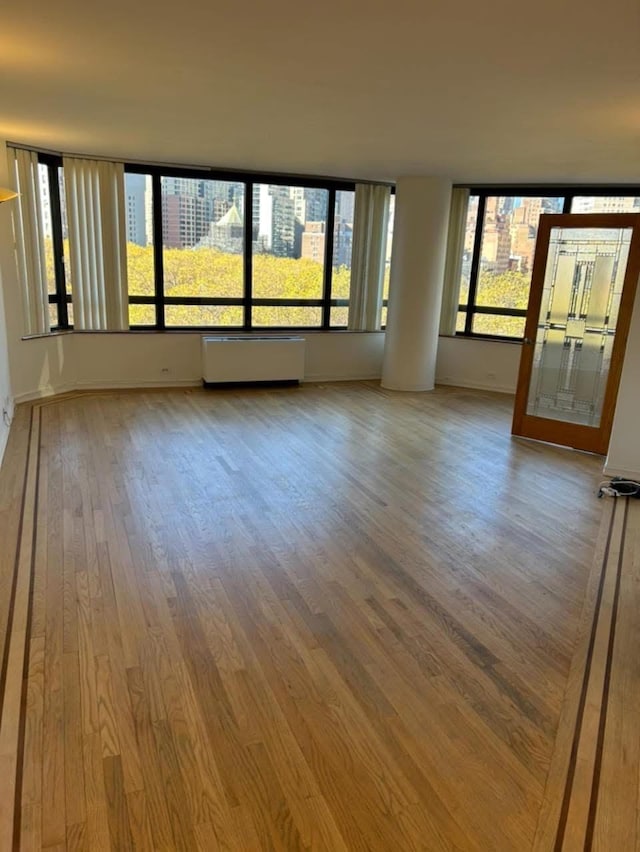 spare room with baseboards and wood finished floors