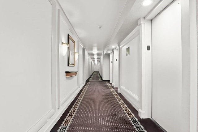 corridor with dark colored carpet and baseboards