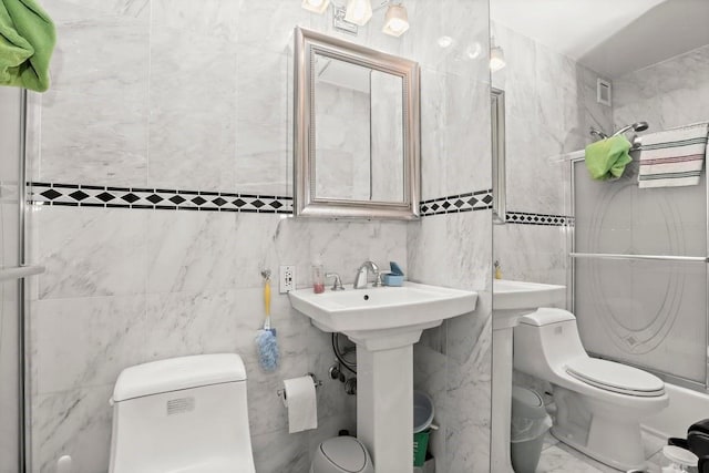 bathroom with a sink, toilet, tile walls, visible vents, and a stall shower