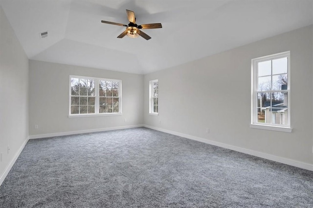 carpeted empty room featuring a raised ceiling, vaulted ceiling, and ceiling fan