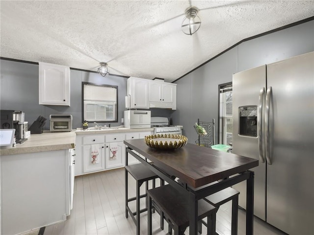 kitchen featuring a textured ceiling, white cabinetry, white appliances, and light wood-type flooring