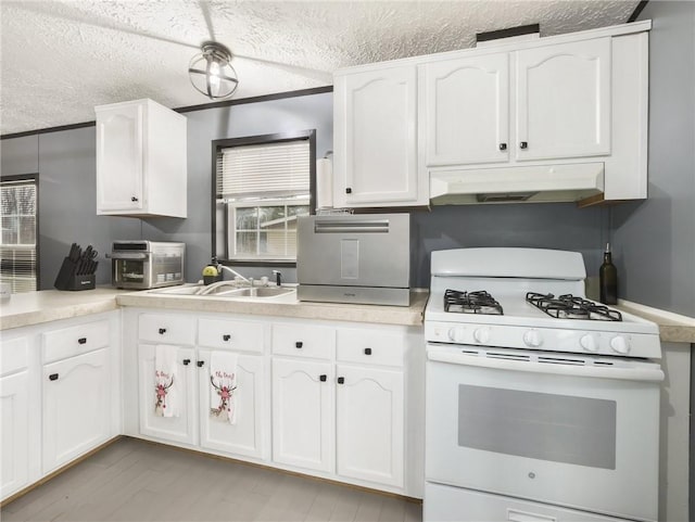 kitchen with a textured ceiling, white gas range oven, white cabinetry, and sink