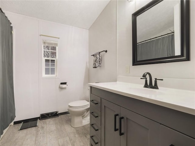 bathroom featuring a textured ceiling, toilet, lofted ceiling, vanity, and hardwood / wood-style flooring