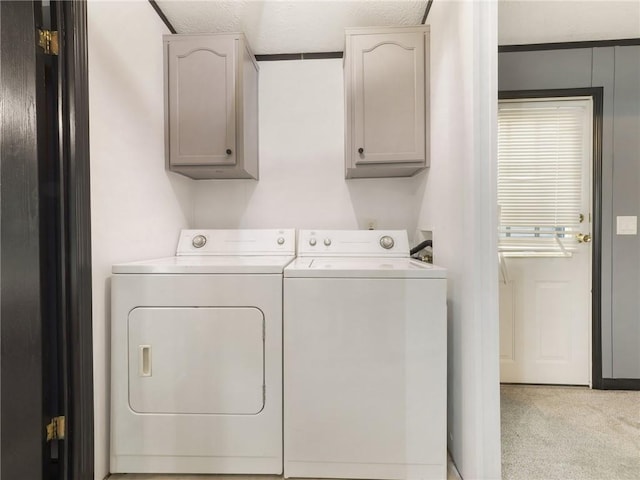 washroom with separate washer and dryer, light colored carpet, cabinets, and a textured ceiling