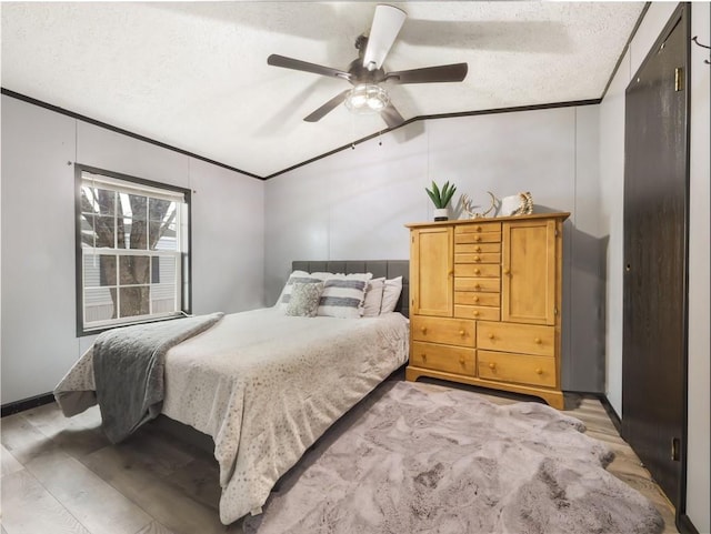 bedroom featuring ceiling fan, light wood-type flooring, vaulted ceiling, a textured ceiling, and ornamental molding