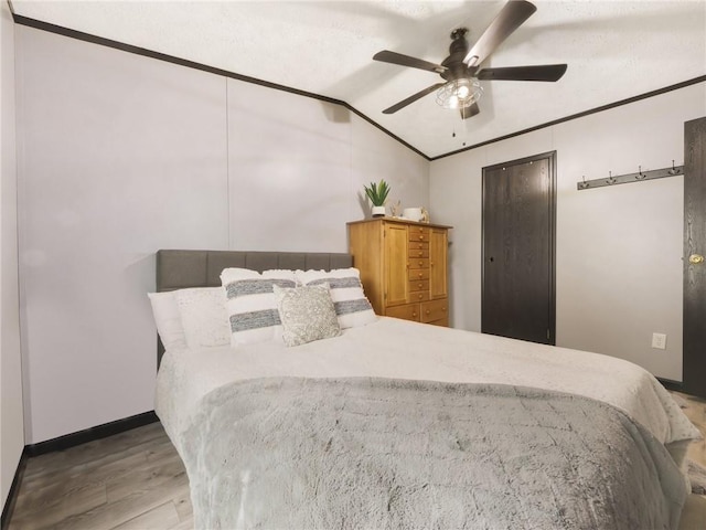 bedroom with light hardwood / wood-style floors, vaulted ceiling, ceiling fan, and crown molding