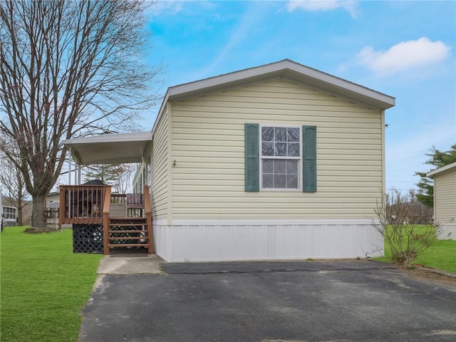 view of side of property with a carport, a deck, and a lawn