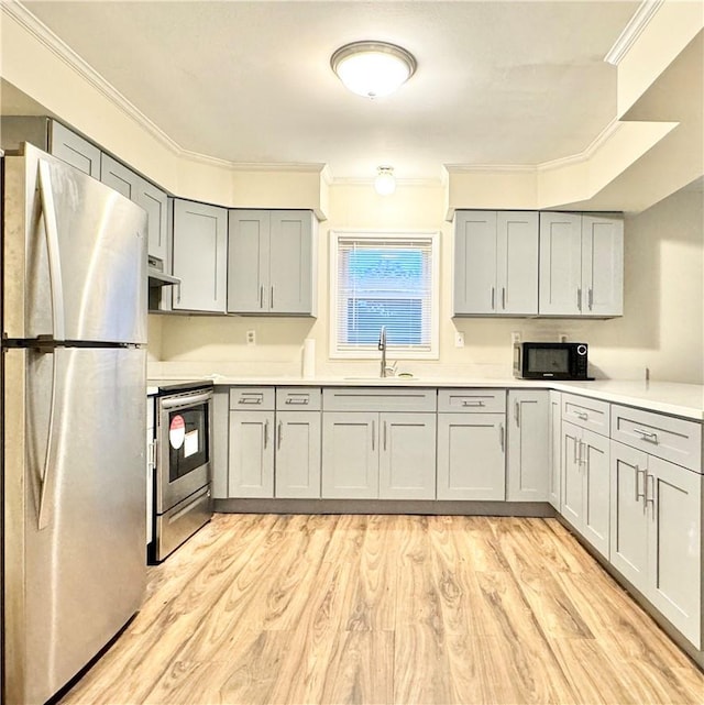 kitchen with sink, stainless steel appliances, light wood-type flooring, and ornamental molding