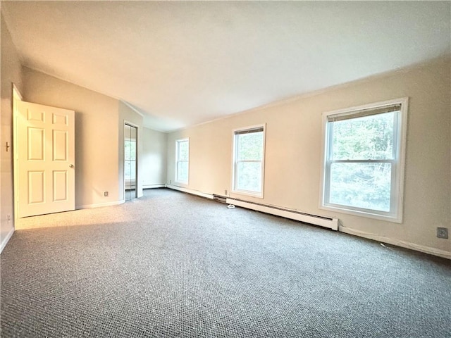 empty room with carpet flooring, lofted ceiling, and a baseboard heating unit